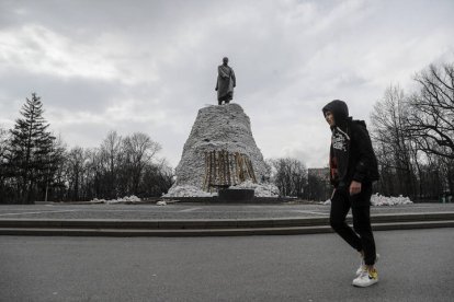Un joven pasa ante la estatua dedicada al poeta ucraniano Taras Sevchenko, portegida por sacos terreros, en el parque del mismo nombre de la ciudad de Jarkiv. MANUEL BRUQUE