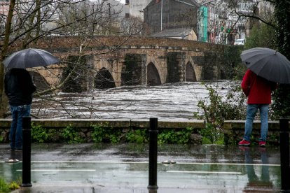 Dos hombres miran el caudal del río Miño que pasa bajo el Puente Romano de Lugo. ELISEO TRIGO