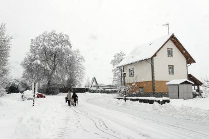 Dos personas caminan por una calle de la localidad de espinal donde la situación meteorológica mejora este martes esperando que el temporal se vuelva a recrudecer a partir de esta tarde y la jornadas siguientes donde se esperan intensas nevadas. JESÚS DIGES