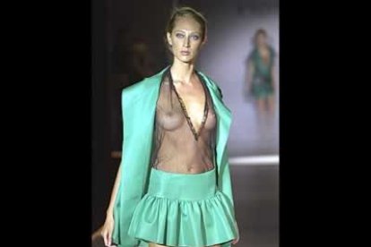 Minifalda de vuelo y chaqueta sin mangas de amplias solapas en verde esmeralda, sobre top de tul negro.