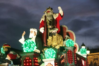 Melchor saluda con entusiasmo a los niños leoneses mientras sus pajes tiran miles de piruletas y caramelos. RAMIRO
