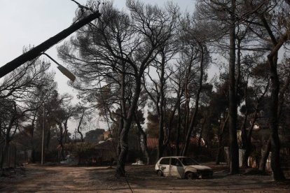 Un coche quemado tras el mayor incendio de la zona urbana de Varybobi (Atenas, Grecia). Los refuerzos fueron enviados desde todo el país para acabar con las llamas que ayer seguían aún consumiento el suburbio. EFE/EPA/YANNIS KOLESIDIS