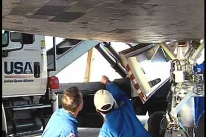 Los astronautas Steve Robinson y Soichi Noguchi examinan la superficie del Discovery.