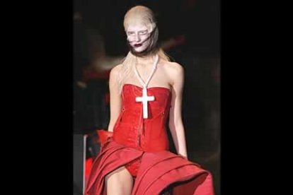 Los abrigos se abren sobre vestidos color carne, con botas y un crucifijo sobre el pecho como accesorios.