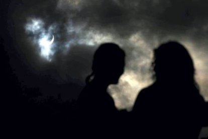 Un grupo de personas observan cómo la Luna pasa por delante del Sol, en Cairns. TIM WIMBORNE | REUTERS