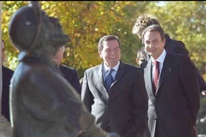 Schröder y Zapatero pasan por delante de la escultura dedicada a todos los peregrinos que pasan por León, camino de Santiago.