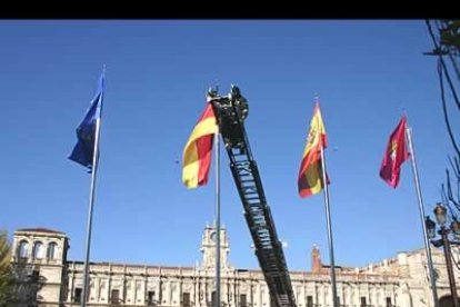 Miembros del Cuerpo de Bomberos, ayudados por una grúa, colocan la bandera de Alemania ante el Hostal Parador de San Marcos antes del inicio de la cumbre.