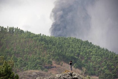 Una mujer observa la erupción de La Palma subida a una antigua colada volcánica en el municipio de El Paso. CARLOS DE SAÁ