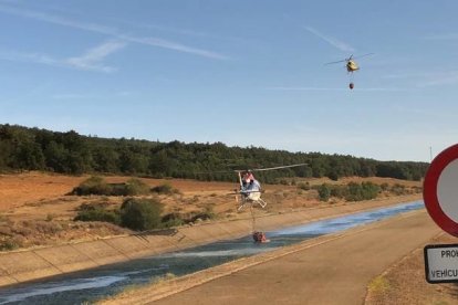 Dos helicópteros recogen agua de un canal para sofocar el incendio en Villapadierna. RAMIRO