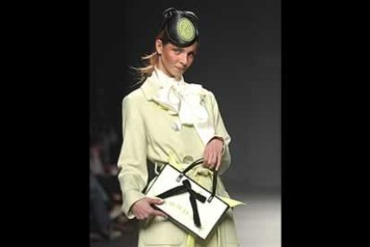 Abrigo de lana verde claro con grandes botones, blusa de raso con lazada y complementos en verde, blanco y negro. Se trata de un diseño de los canarios TRAStornados, José Enrique García y Paco Navarro