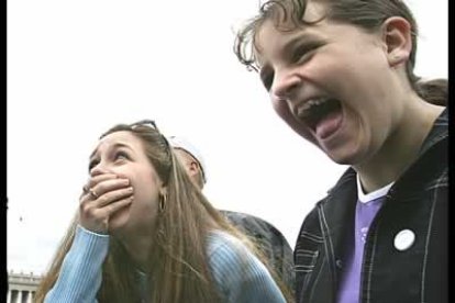 Dos chicas observan las primeras nubes de humo blanco en la chimenea de la basílica.