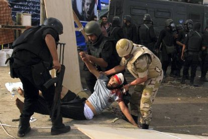Policías antidisturbios y un soldado atienden a un manifestante herido. REUTERS