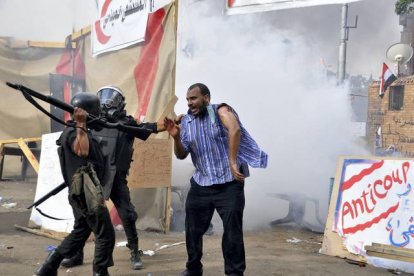 Dos antidisturbios golpean a un hermano musulmán para alejarle del campamento. AFP / ENGY IMAD