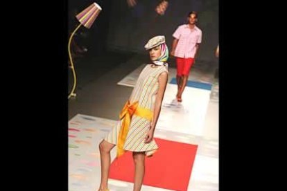 Vestido evasé con rayas multicolores, recogido a la cadera con cinturón de raso que se anuda enlazada.