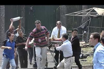 Operarios australianos e indonesios ayudan a evacuar a uno de los heridos por el atentado.