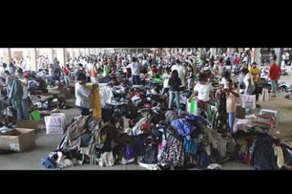 Cientos de evacuados de Nueva Orleans buscan ropa y asistencia en uno de los refugios de Texas. Ante la avalancha de damnificados, este estado ordenó un puente aéreo hacia otros como Utah y Nueva York.