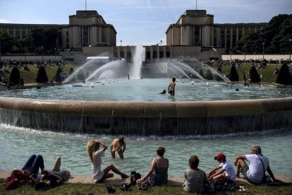 óvenes toman el sol y se refrescan en la explanada de Trocadero, en París. / CHRISTOPHE ARCHAMBAULT (AFP)