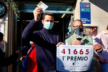 Uno de los agraciados muestra este jueves el décimo ganador del primer premio del sorteo extraordinario de la lotería del Niño junto a los trabajadores de la Administración de Lotería número 6 de Logroño.