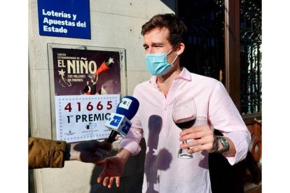 El responsable de la Administración de Lotería número 6 de Logroño, Ángel Alda (d), atiende a la Agencia Efe  mientras celebra a las puertas de la administración tras vender números del 41.665, agraciado con el primer premio del sorteo extraordinario de la lotería del Niño.  EFE / RAQUEL MANZANARES