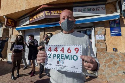 El gerente de la administración de lotería de la pedanía murciana de Sangonera la Seca, Antonio Garnés (c), posa este jueves mientras celebra la venta de números del 44.469, agraciado con el segundo premio del sorteo extraordinario de la lotería del Niño. EFE/MARCIAL GUILLÉN