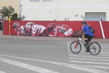 Un ciclista pasa por delante del mural alusivo a la Vuelta a España 2023 situado en la calle Julio Hernández de La Bañeza. RAMIRO