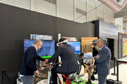 El consejero de Medio Ambiente, Vivienda y Ordenación del Territorio, Juan Carlos Suárez-Quiñones, prueba la realidad virtual para conocer dos rutas de la Zona Alfa León compañado por el delegado de la Junta, Eduardo Diego, en la feria de turismo Intur. DL
