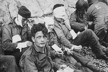 Soldados estadounidenses del 16º Regimiento de Infantería que han resultado heridos en la playa Omaha mientras esperan su evacuación a un hospital de campaña durante el desembarco de Normandía .