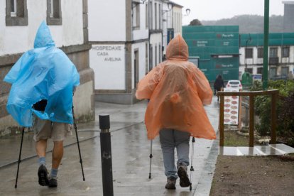 arios peregrinos se protegen del viento y la lluvia, este miércoles en Palas de Rei. EFE/ Eliseo Trigo