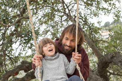 Padre columpiando a su hijo pequeño en un parque. Freepik