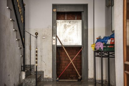 Dos cepillos cruzados señalizan el hueco de un ascensor averiado por la inundación en Paiporta. EFE/Biel Aliño