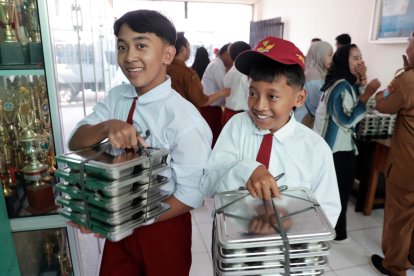 Estudiantes de Primaria llevan este lunes bandejas de comida en la escuela primaria Lengkong 1 en Tangerang en el primer día oficial del programa de comidas gratis para escolares y mujeres embarazadas en Indonesia. EFE/EPA/ADI WEDA