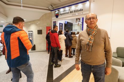 El lotero de la Administración de Loterías de El Corte Inglés de León, Basilio Miguélez, junto al establecimiento que vendió el primer premio del Sorteo del Niño.