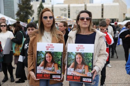 Unas mujeres con fotos de la rehén israelí Naama Levy observan en Tel Aviv una transmisión en vivo en una pantalla grande la liberación de cuatro soldados israelíes secuestradas, quienes están siendo entregadas por Hamás a la Cruz Roja, el 25 de enero de 2025. EFE/EPA/ABIR SULTAN