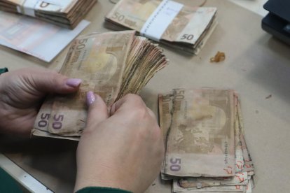 Una trabajadora del Área de Operaciones con Efectivo Banco de Portugal maneja un fajo de billetes de 50 euros estropeados por la humedad. EFE/Carlos Caselles