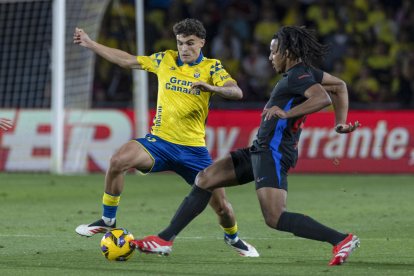 El defensa francés del FC Barcelona, Jules Koundé (d), disputa el balón ante el defensa de la UD Las Palmas, Álex Muñoz, durante el encuentro correspondiente a la jornada 25 de Laliga EA Sports que disputaron en el estadio de Gran Canaria. EFE / Quique Curbelo.