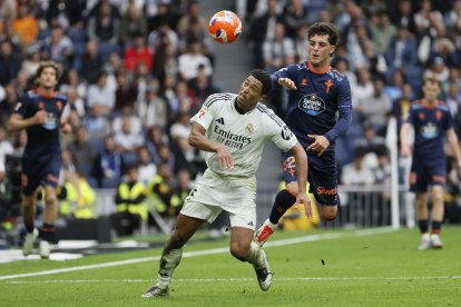 El centrocampista británico del Real Madrid Jude Bellingham (i) lucha por el balón con el delantero del Celta de Vigo Hugo Álvarez durante el partido entre el Real Madrid y el Celta este domingo en el estadio Santiago Bernabéu en Madrid este domingo. EFE/ Ballesteros