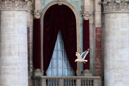 Un pájaro vuela junto al balcón de la Basílica de San Pedro, desde donde aparecerá el nuevo Papa, en el Vaticano.