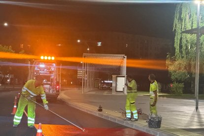 Operarios pintan el carril de rojo durante la noche.