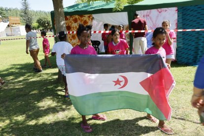 Varias niñas extienden la bandera saharaui en el campamento improvisado en las piscinas.