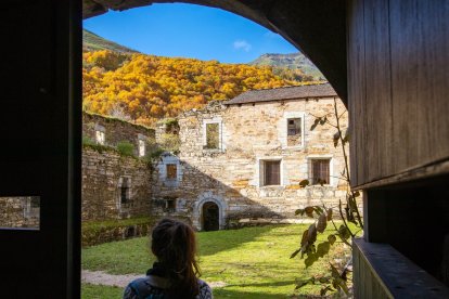 Mujer contemplando las ruinas del monasterio de San Pedro de Montes con el bosque otoñal de fondo