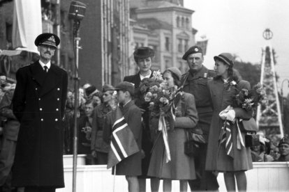 El rey Haakon VII de Noruega (izq.) se dirige a la multitud en Radhusplassen, acompañado por la familia del príncipe heredero —el príncipe heredero Olav, la princesa heredera Marta, el príncipe Harald (2.º por la der.) y las princesas Ragnhild y Astrid— durante las celebraciones de los Días de la Paz de 1945.