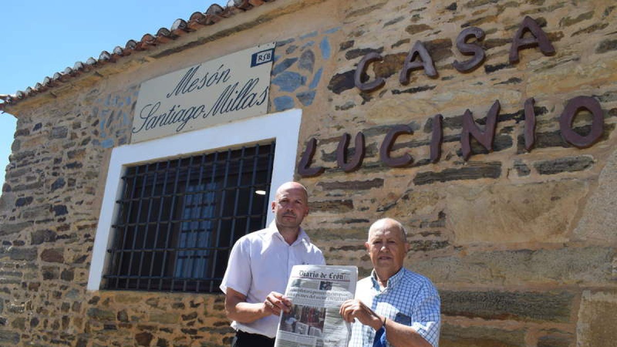 Toño y Lucinio frente a las puertas del mesón posando con un ejemplar del Diario de León que no ha faltado nunca en casi 40 años. A. R.