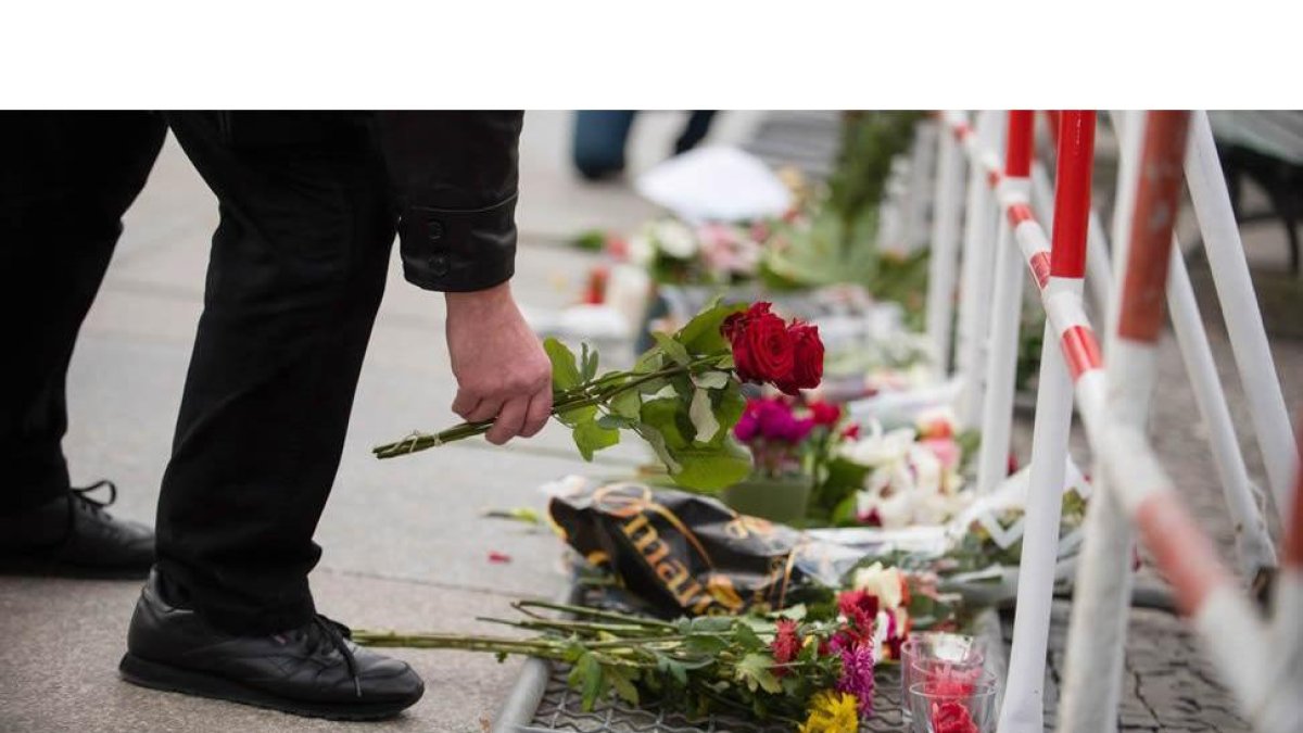 Un hombre deposita flores en la embajada de Francia en Berlín.