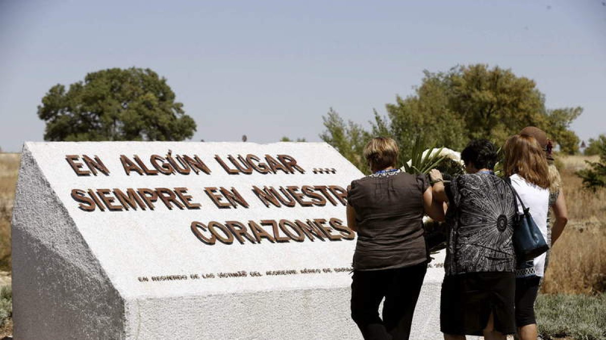 Familiares de los fallecidos colocan flores blancas en el monumento en su recuerdo.