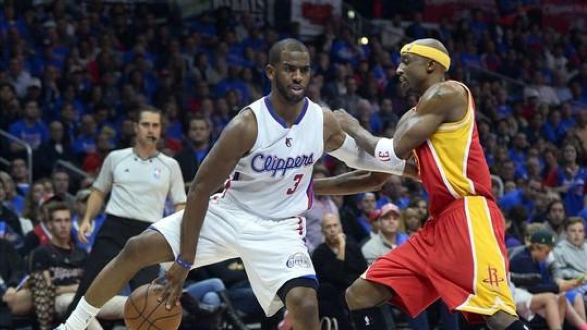 Chris Paul, de los Clippers, da un pase atrás bajo las piernas ante Jason Terry, de los Rockets.