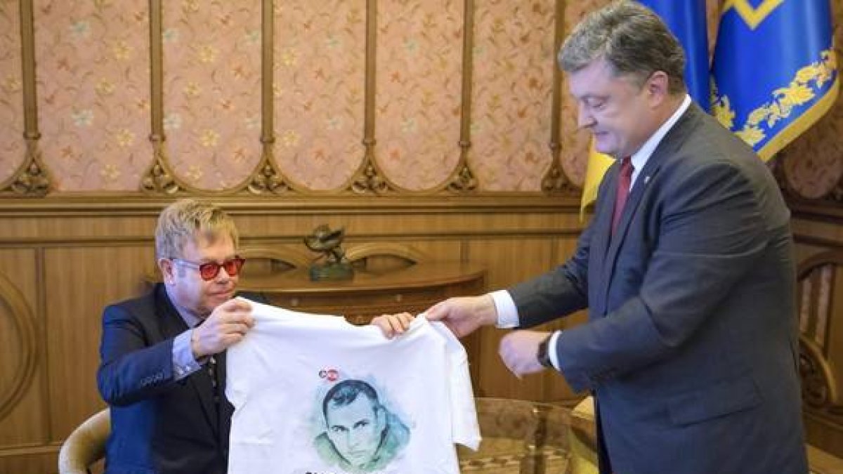 El presidente ucraniano, Petro Poroshenko, entrega una camiseta con la imagen de un cineasta encarcelado en Rusia al cantante Elton John.