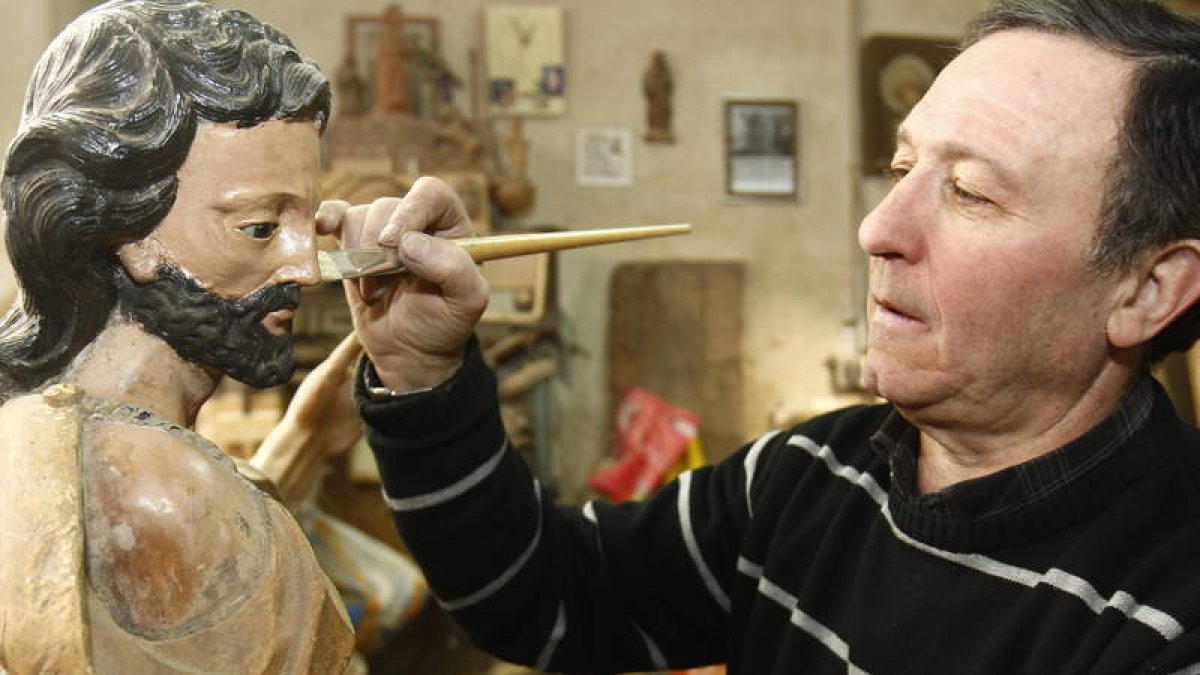 El leonés Jesús Fernández retoca una de las piezas para restaurar con las que trabaja en su taller, donde se dedica a un oficio que le viene de familia.