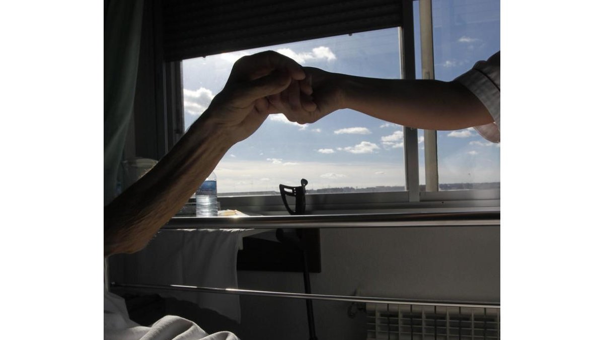 Un paciente y una enfermera se estrechan la mano en una de las habitaciones del Hospital San Juan de Dios de León