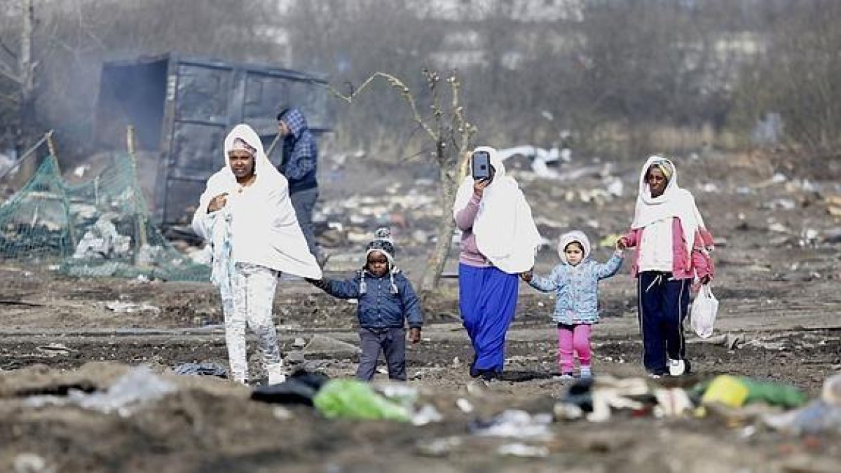 Refugiadas caminan con sus hijos por el campamento de Calais durante su desmantelamiento.