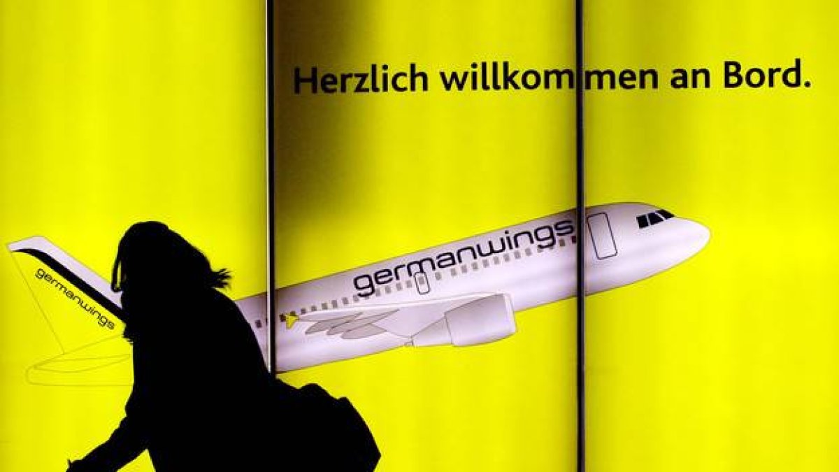 Una mujer pasea por delante de un cartel publicitario de Germanwings en el aeropuerto de Colonia, en Alemania.